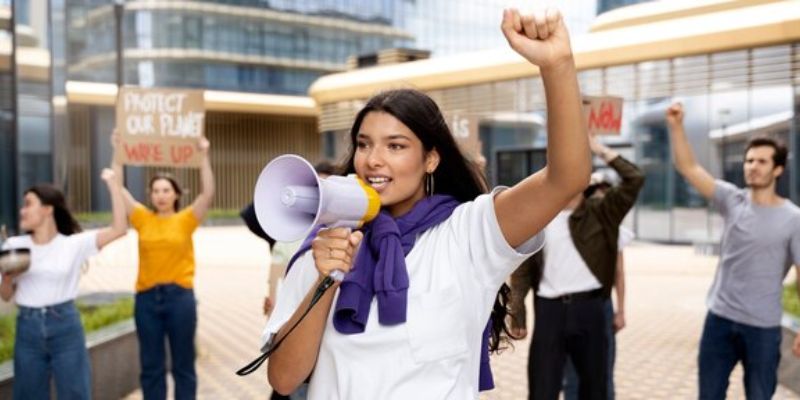 Uma mulher branca segurando um megafone enquanto faz um protesto solicitando direitos trabalhistas, simbolizando os serviços oferecidos para entidades sindicais de Brazlândia pelo Ministério do Trabalho.